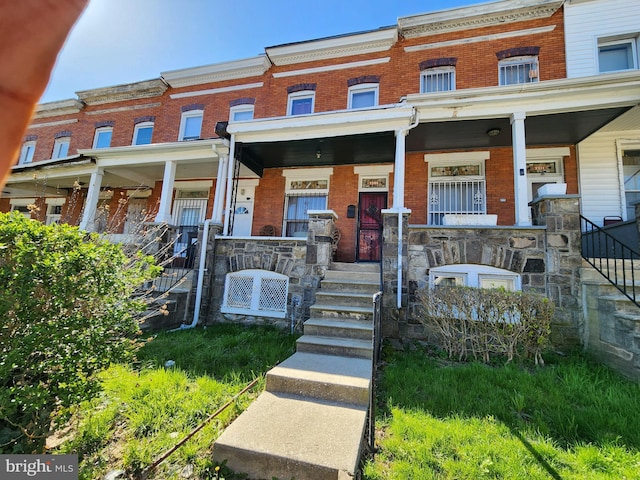 townhome / multi-family property featuring brick siding, a porch, and stairs