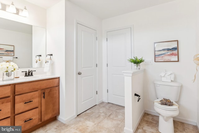 bathroom featuring toilet, tile patterned flooring, vanity, and baseboards