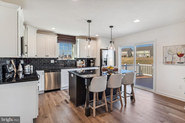 kitchen with decorative backsplash, appliances with stainless steel finishes, white cabinets, dark countertops, and a sink