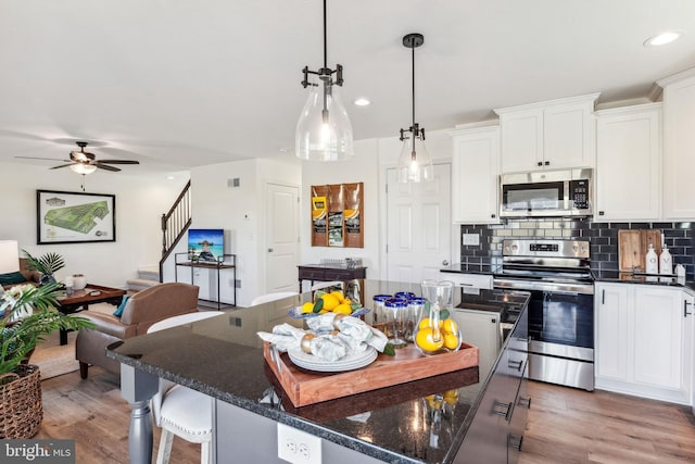kitchen featuring tasteful backsplash, light wood-type flooring, a ceiling fan, white cabinetry, and appliances with stainless steel finishes