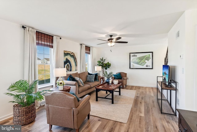 living area with visible vents, a ceiling fan, light wood-style flooring, and baseboards
