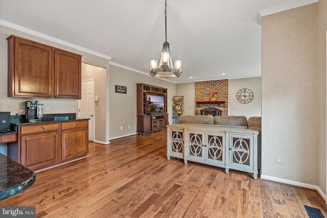 9804 Luck Penny Ct, Bristow, VA 20136 - kitchen with light wood-type flooring, baseboards, a chandelier, brown cabinetry, and crown molding