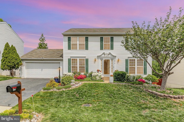 colonial-style house with driveway, a front yard, and an attached garage