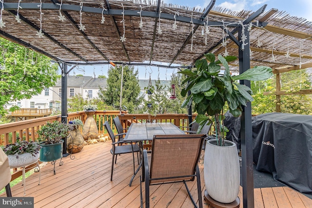 deck with a grill, outdoor dining area, and a pergola