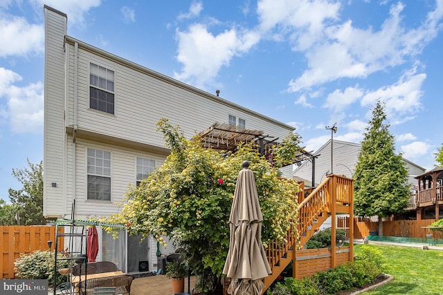 rear view of house featuring a pergola, stairs, a yard, and fence
