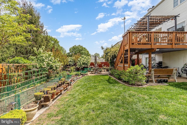 view of yard featuring a patio, fence, a wooden deck, and a vegetable garden