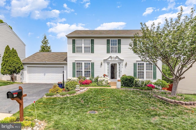 colonial house with a front lawn, driveway, and a garage