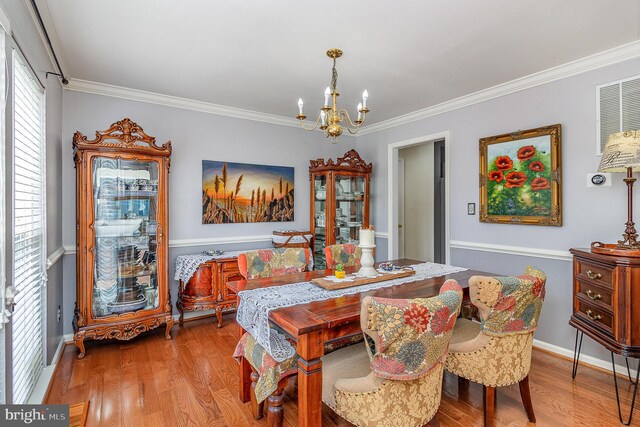 dining space featuring ornamental molding, wood finished floors, a chandelier, and baseboards