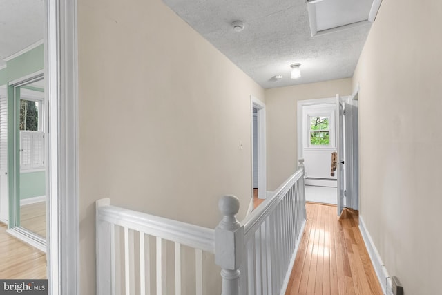 1822 Clearwood Rd, Baltimore, MD 21234 - hallway featuring an upstairs landing, a baseboard radiator, light wood finished floors, baseboards, and a textured ceiling