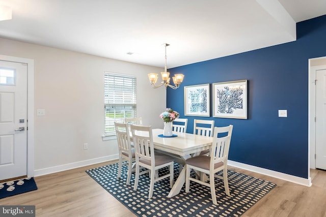 dining space with baseboards, light wood finished floors, a notable chandelier, and visible vents