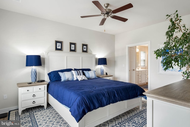 bedroom featuring a ceiling fan, baseboards, and ensuite bath