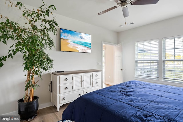 bedroom featuring baseboards, ceiling fan, wood finished floors, and visible vents
