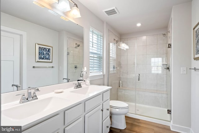 bathroom with visible vents, a shower stall, a sink, and wood finished floors