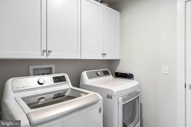 laundry area featuring separate washer and dryer and cabinet space