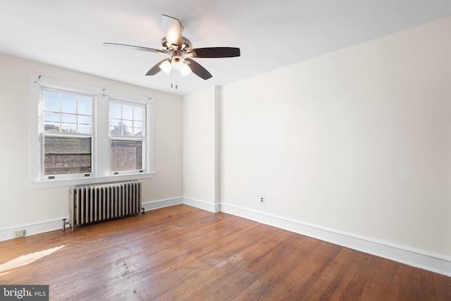 empty room featuring baseboards, radiator, ceiling fan, and wood finished floors