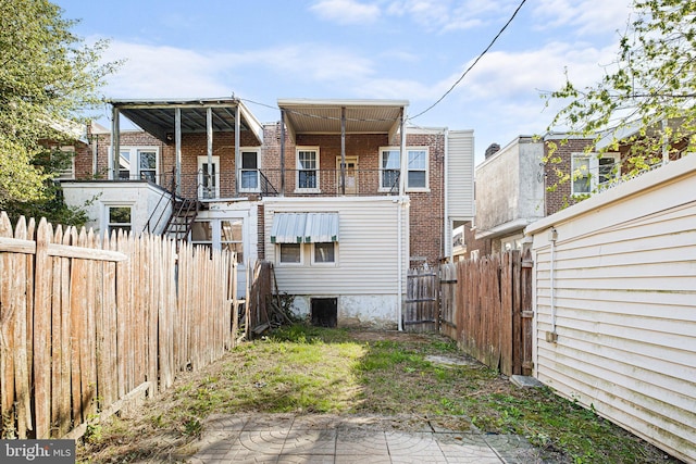 rear view of house featuring brick siding and fence