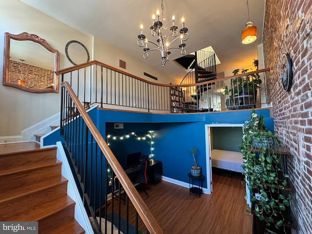 stairs featuring an inviting chandelier, baseboards, and wood finished floors