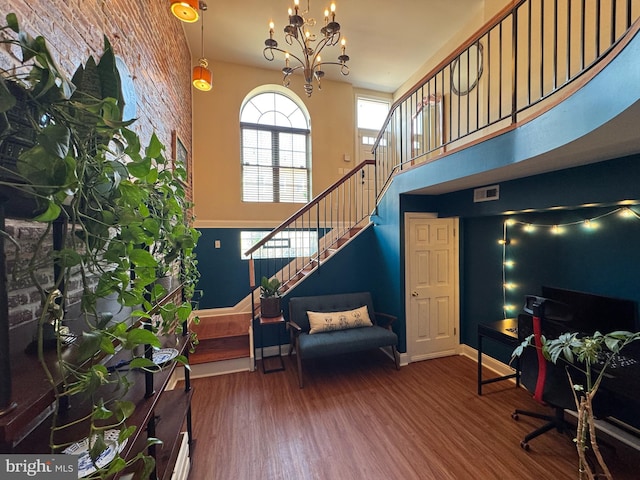 foyer with visible vents, stairs, wood finished floors, a high ceiling, and a notable chandelier