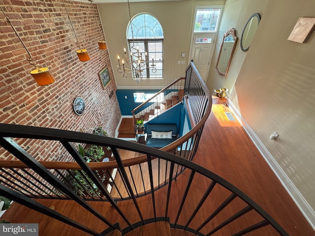 stairs featuring visible vents, a notable chandelier, wood finished floors, and brick wall