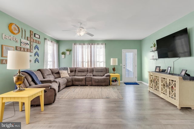 living room featuring a ceiling fan, wood finished floors, and baseboards