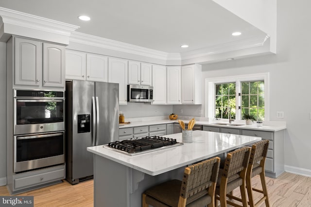 1418 Woodhurst Blvd, Mclean, VA 22102 - kitchen with appliances with stainless steel finishes, ornamental molding, a breakfast bar area, light stone counters, and a center island