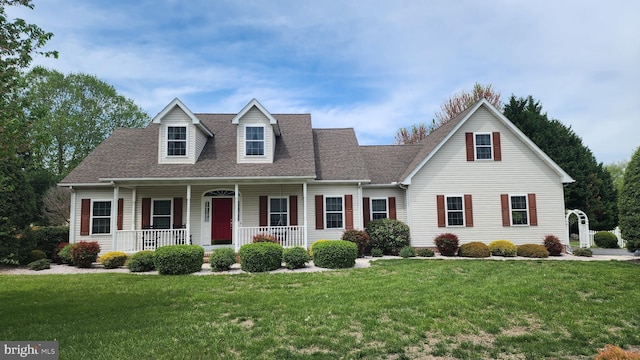 new england style home featuring a front lawn, a shingled roof, and covered porch