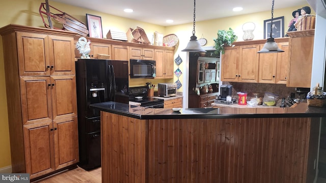 kitchen featuring dark countertops, black appliances, light wood finished floors, a peninsula, and hanging light fixtures