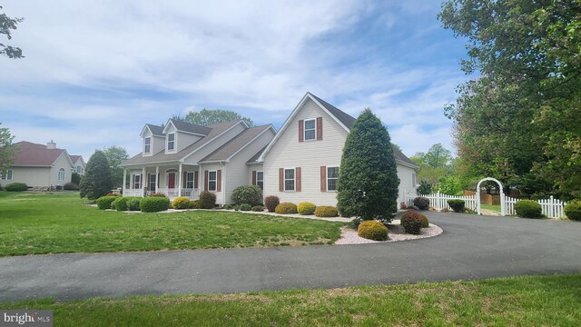 cape cod home with fence, a front yard, and a porch