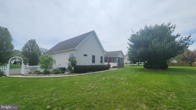 view of property exterior featuring fence, a yard, and a sunroom