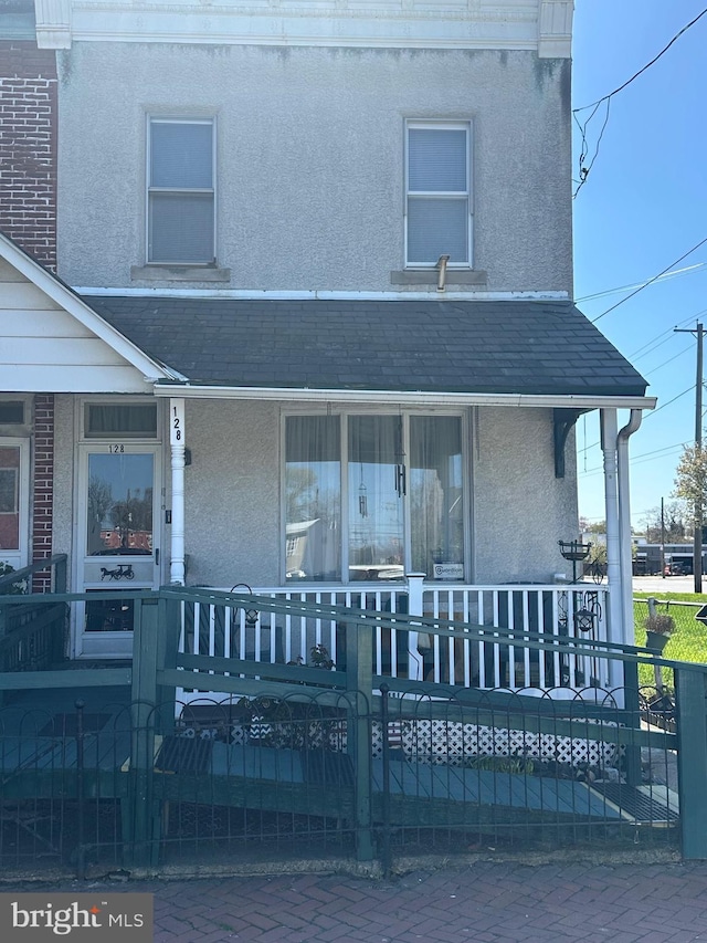 128 Thurlow St, Chester, PA 19013 - view of front of house with covered porch, fence private yard, roof with shingles, and stucco siding