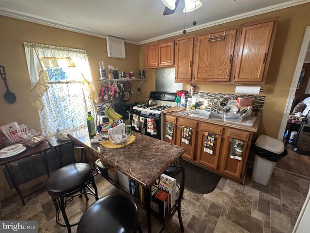128 Thurlow St, Chester, PA 19013 - kitchen with crown molding, brown cabinetry, a ceiling fan, stone finish flooring, and white range with gas cooktop