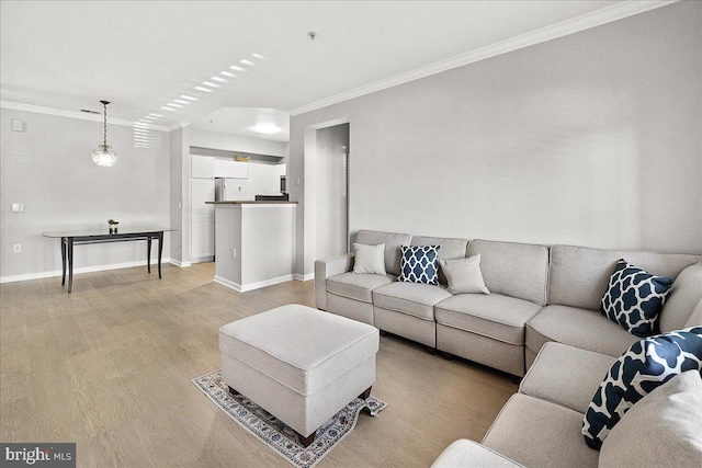 living area with baseboards, light wood-type flooring, and crown molding