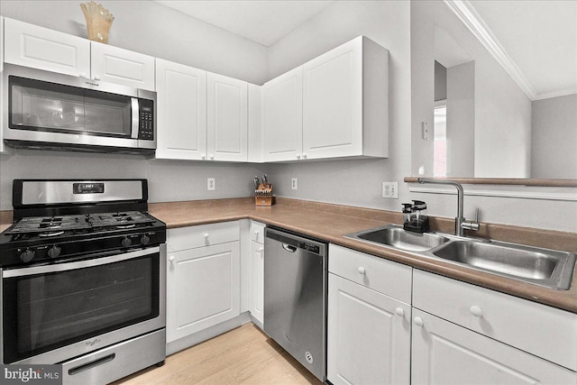 kitchen featuring white cabinetry, stainless steel appliances, ornamental molding, and a sink