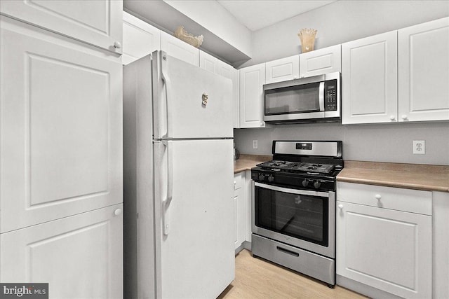 kitchen featuring white cabinetry, stainless steel appliances, and light wood-style floors