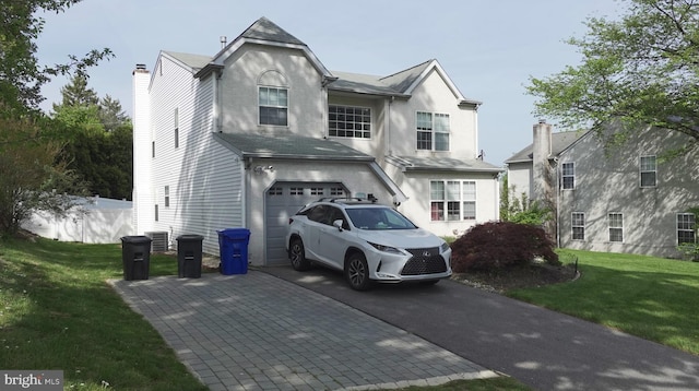 view of front of home featuring stucco siding, a garage, driveway, central AC, and a front yard