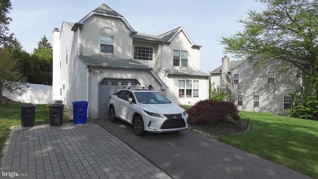 view of front of property featuring a garage, aphalt driveway, a front lawn, and stucco siding