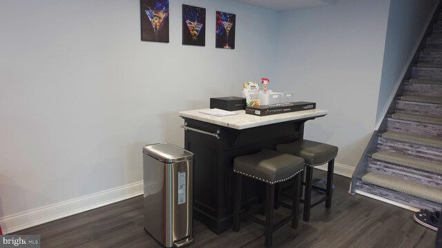 bar with dark wood finished floors, stairs, and baseboards