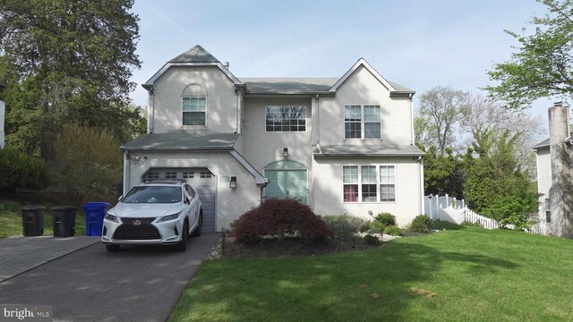 traditional home featuring stucco siding, fence, a garage, driveway, and a front yard