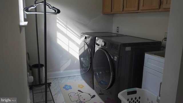 washroom featuring baseboards, washer and dryer, cabinet space, and marble finish floor