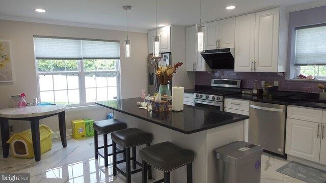 kitchen with decorative backsplash, appliances with stainless steel finishes, white cabinets, ornamental molding, and ventilation hood