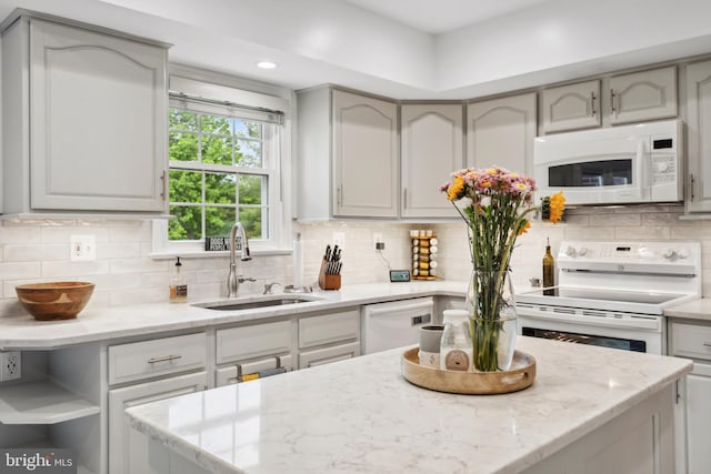 kitchen featuring white appliances, a sink, decorative backsplash, light stone counters, and recessed lighting