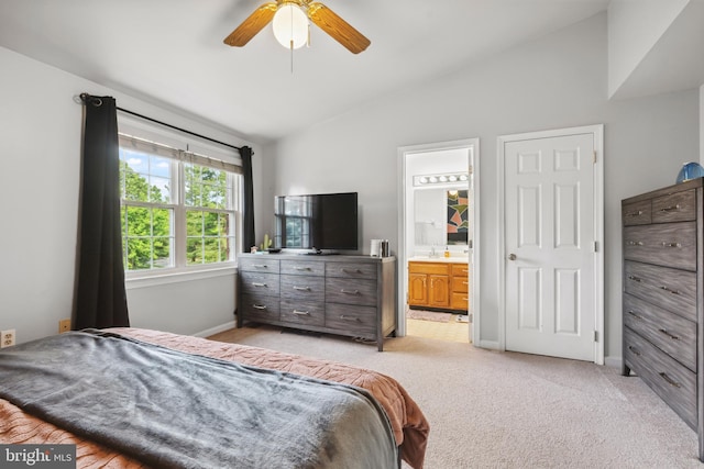 bedroom with lofted ceiling, light carpet, a sink, baseboards, and ensuite bath