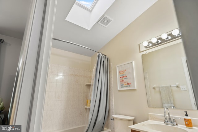 bathroom featuring a skylight, toilet, vanity, and shower / bath combo with shower curtain