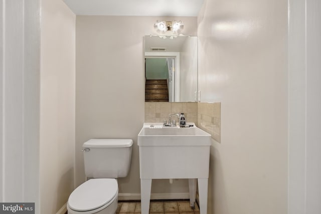 bathroom with backsplash, baseboards, and toilet