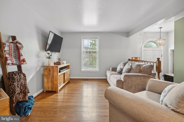 living area with light wood-type flooring, baseboards, and a chandelier