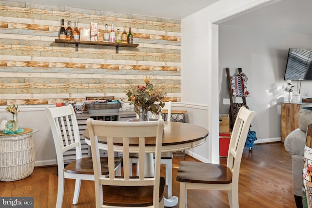 dining room with wood finished floors, wooden walls, and baseboards