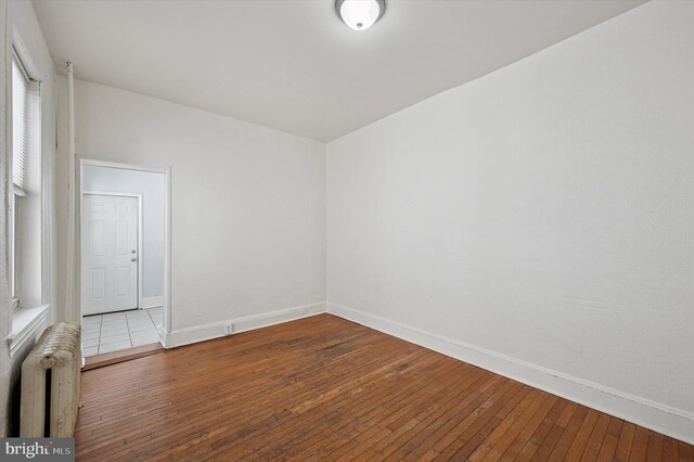 spare room with baseboards, radiator, and hardwood / wood-style floors