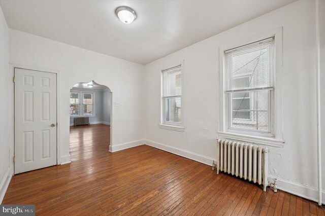 spare room with a healthy amount of sunlight, wood-type flooring, and radiator