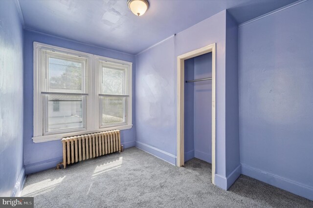 unfurnished bedroom featuring baseboards, radiator heating unit, a closet, and carpet