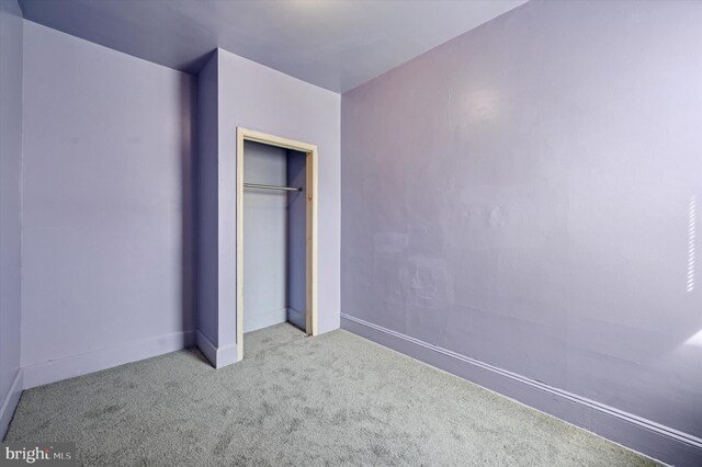 unfurnished bedroom featuring baseboards, carpet floors, and a closet